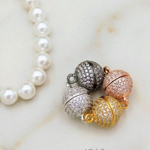 May include: Three magnetic clasps for necklaces or bracelets. The clasps are round and have a pave setting of clear cubic zirconia stones. The clasps are in gold, silver, and rose gold tones.