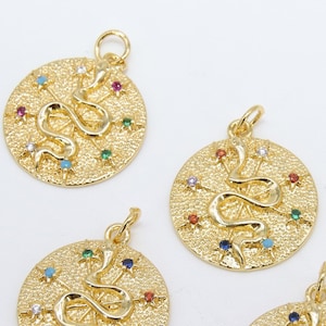 May include: Five gold-toned pendants with a snake design and colorful gemstones. Each pendant is round and has a textured surface. The pendants are arranged in a semi-circle on a white background.