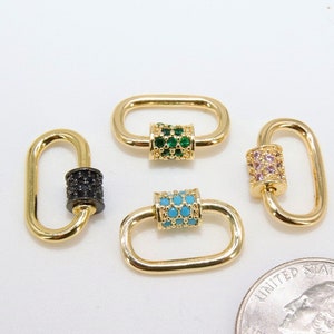 May include: Four gold-colored oval-shaped clasps with decorative center bars. One clasp has a black center, another has green gems, a third has turquoise gems, and the last has pink gems. A quarter is included for size reference.