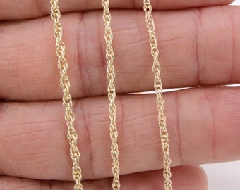 May include: Three gold chains of different lengths, laid out on a hand. The chains are all the same style, with a twisted rope design.