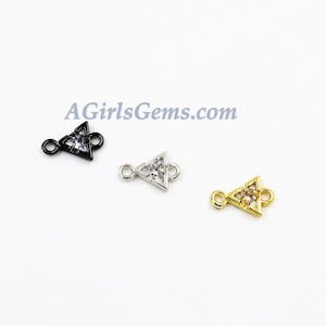 Puede incluir: Tres abalorios de conexión en forma de triángulo con piedras de circonita cúbica transparentes. Los abalorios son de color negro, plateado y dorado.