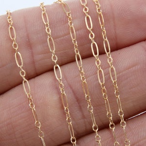 May include: Close-up of delicate gold-colored chain. The chain features a repeating pattern of small oval and elongated rectangular links. The jewelry is displayed against a neutral background.