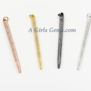 May include: Four long, thin, silver, gold, rose gold, and black pendants with a row of small clear rhinestones.  A Girls Gems.com is printed on the white background.