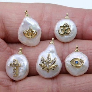 May include: Six white baroque pearl charms with gold accents and various symbols including a crown, an Om symbol, a marijuana leaf, a cross, and an evil eye.