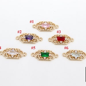 May include: Six gold-tone metal connector charms with different coloured gemstones. Each charm features a filigree design and a rectangular gemstone in the centre. The gemstones are pink, purple, red, clear, green, and light blue.