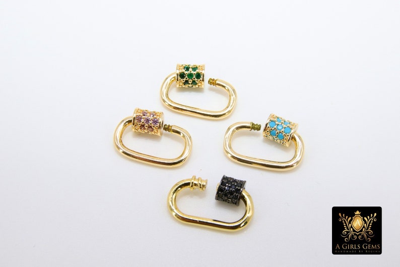 May include: Four gold-colored carabiner clasps with decorative, gem-studded screw-on ends. The gems are in various colors: green, purple, turquoise, and black. The clasps are on a white background.