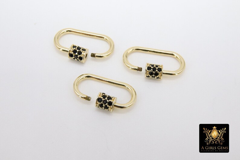 May include: Three gold-colored oval screw lock clasps with black gem accents. The clasps are open, revealing the screw threads. The background is plain white. The clasps are likely for jewelry making.