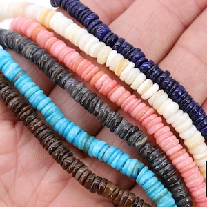 May include: Assortment of colorful shell beads, including turquoise, pink, white, brown, and blue. The beads are strung together on a string and are ready to be used for jewelry making.