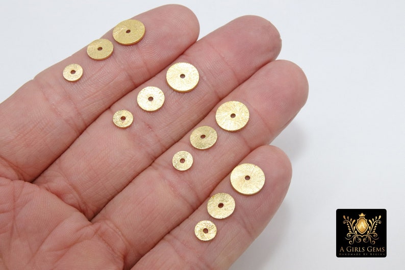 May include: Assortment of gold-colored metal round sequins of varying sizes. The sequins have a textured surface and a hole in the center.