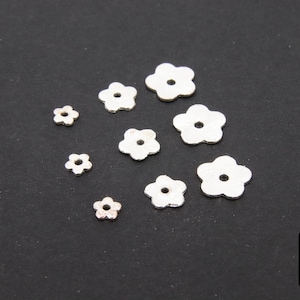 May include: Assortment of silver-colored metal flower-shaped charms of varying sizes.