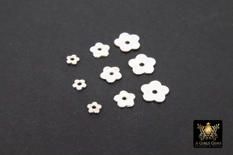 May include: Assortment of silver-colored metal flower-shaped charms of varying sizes.
