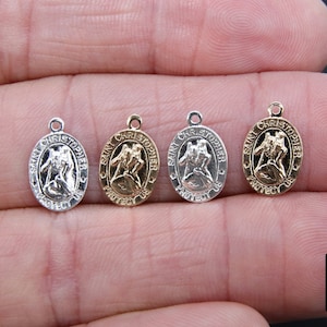 Könnte beinhalten: Vier ovale Saint-Christopher-Medaillen mit einer goldenen, silbernen und zwei silbernen Oberflächen. Die Medaillen zeigen ein erhabenes Bild des Heiligen Christopherus, der ein Kind trägt. Der Text "Saint Christopher Protect Us" ist um den Rand jeder Medaille eingraviert.