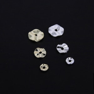 Peut inclure: Assortiment de six dos d'oreille en métal argenté et doré en forme de fleur de différentes tailles.