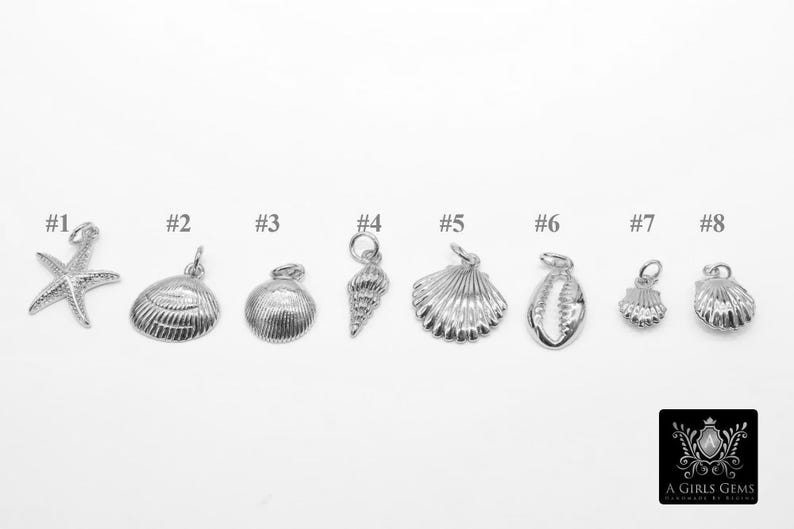 May include: Eight silver charm pendants with different sea-themed designs, including a starfish, seashells, and a conch shell. The charms are numbered 1 through 8.