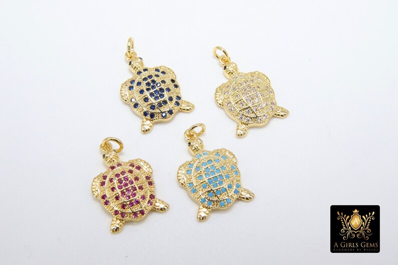 Op de afbeelding: Vier gouden schildpadbedels met verschillende kristalaccenten. De schildpadden zijn versierd met blauwe, witte, roze en turquoise kristallen.