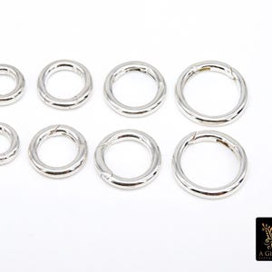 May include: Eight silver jump rings of varying sizes. The rings are open and have a smooth, polished finish.