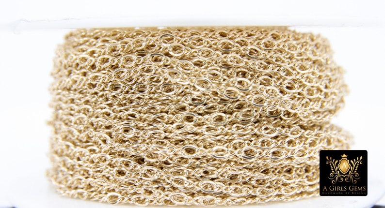 May include: A close-up of a spool of gold-colored chain. The chain is made of small, oval-shaped links.