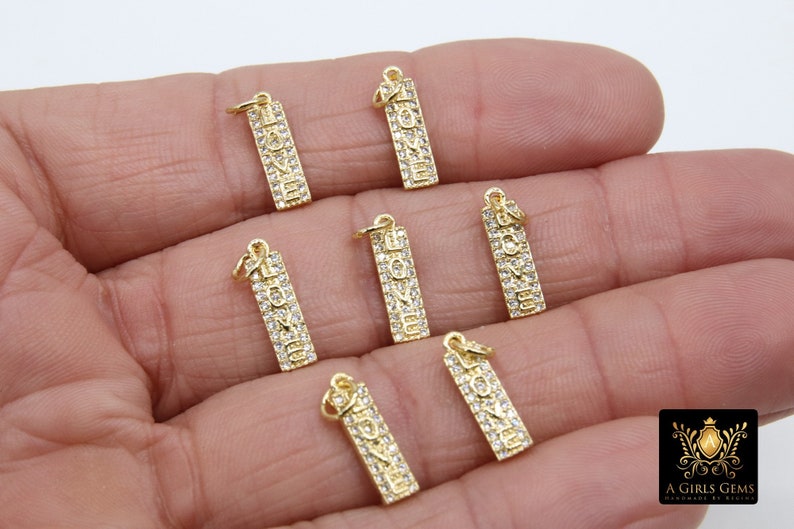 May include: Seven gold-tone charms with clear cubic zirconia stones spelling out the word "LOVE".