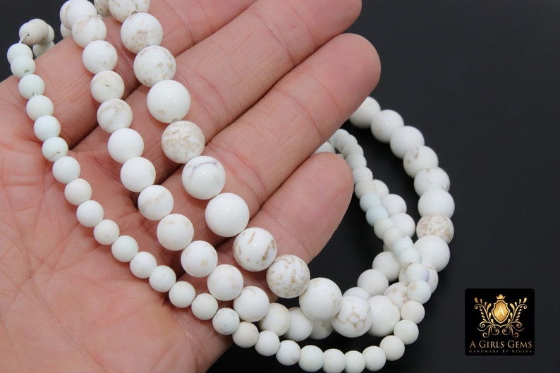 May include: Three strands of white howlite beads, each strand with a different size of round beads. The beads have a natural, marbled look.