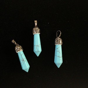 May include: Three turquoise blue pendant charms with silver accents. Each charm is shaped like a pointed teardrop.