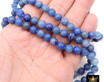 May include: Strands of blue gemstone beads. The beads are a mix of light and dark blue, with a smooth, polished surface. The beads are round and appear to be strung together. The image is well-lit, showing the details of the beads.