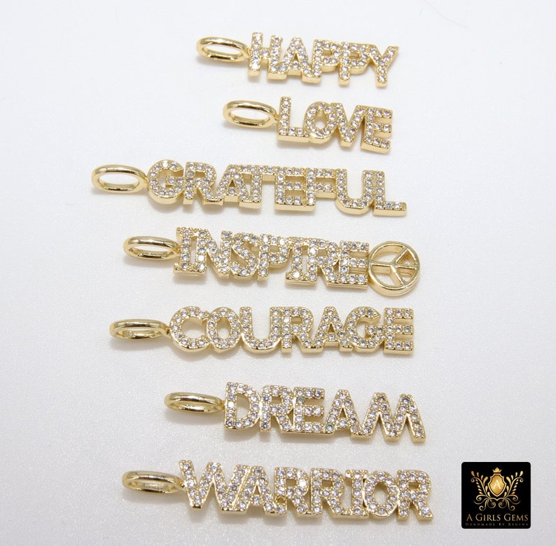May include: Seven gold charms with diamond-like accents spelling out the words "Happy", "Love", "Grateful", "Inspired", "Courage", "Dream", and "Warrior".