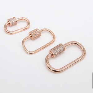 May include: Three rose gold-toned metal clasps with clear crystal embellishments. The clasps are oval-shaped and have a cylinder-shaped closure.