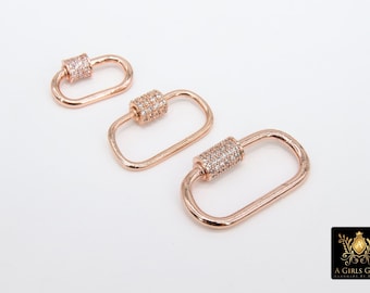 Könnte beinhalten: Drei roségoldfarbene Metallverschlüsse mit klaren Kristallverzierungen. Die Verschlüsse sind oval geformt und haben einen zylindrischen Verschluss.