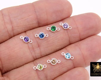 May include: A collection of small, silver-colored gemstone connectors with various colored gemstones, including purple, green, blue, and yellow. Each connector has a small loop on either side of the gemstone. The gemstones are set in a bezel setting.