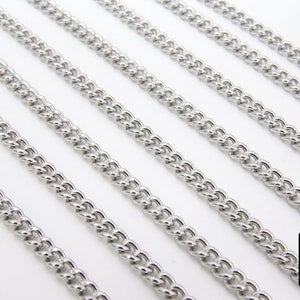May include: Five silver curb chains of different lengths, laid out in parallel lines on a white surface.