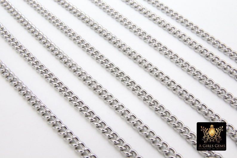 May include: Five silver curb chains of different lengths, laid out in parallel lines on a white surface.