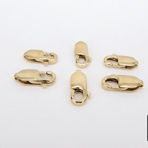 May include: Six gold-toned metal lobster clasps, commonly used for jewelry making.