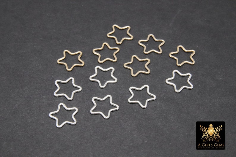 May include: A collection of silver and gold star-shaped jump rings. The jump rings are arranged in a circular pattern on a black background.