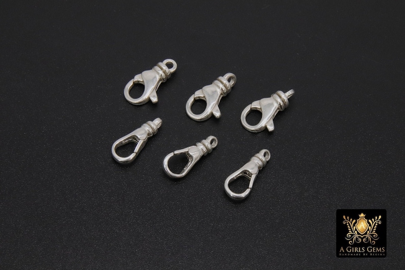 May include: Seven silver-toned lobster clasps, a type of fastener used in jewelry making.