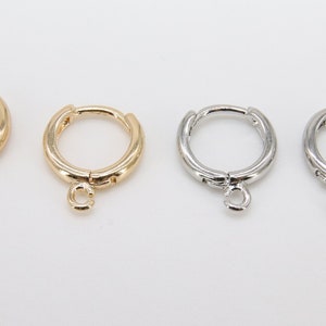 May include: Four hoop earrings with a small charm hanging from each. Two earrings are gold, and two are silver.