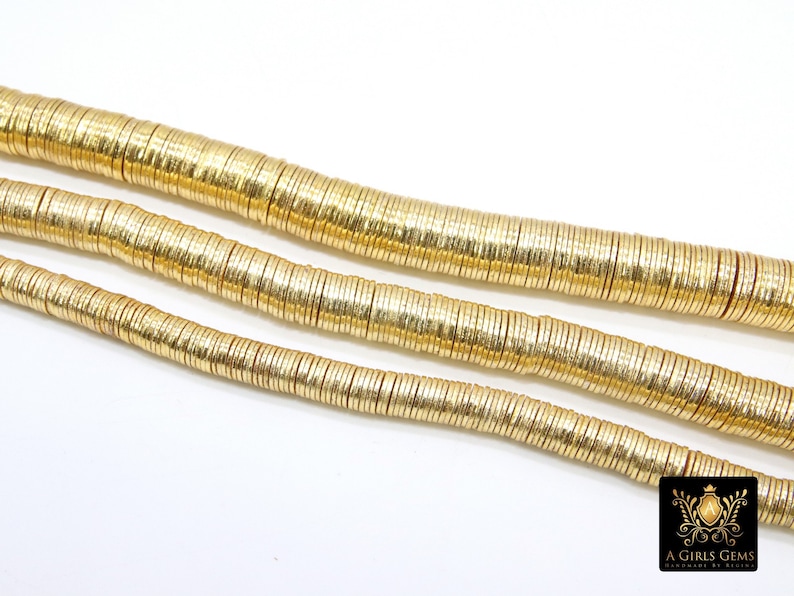 May include: A strand of gold-colored metal beads, each bead is a thin, flat disc with a slightly textured surface. The beads are arranged in a line, with the top row slightly overlapping the bottom row.