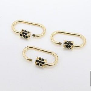 May include: Three gold-colored oval carabiner clasps with black gemstone accents. The clasps are open, showing the screw-on mechanism. The background is plain white. The logo "A Girls Gems" is in the bottom right corner.