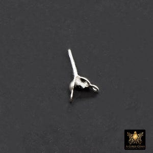 May include: A small, silver-colored jewelry finding with a loop and a small, round bead. A white, fibrous material is attached to the bead. The finding is set against a dark gray background.