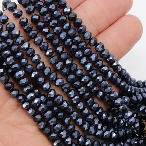 May include: A strand of dark blue faceted glass beads. The beads are small and have a metallic sheen.