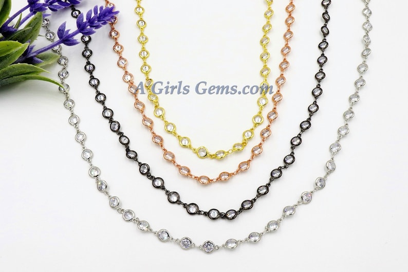 K&ouml;nnte beinhalten: Vier Ketten in verschiedenen Farben mit klaren runden Steinen. Die Ketten sind silber, schwarz, ros&eacute;gold und gold. Die Ketten sind alle gleich lang und liegen in einer Reihe. Der Text "AGirlsGems.com" ist in der Mitte des Bildes sichtbar.