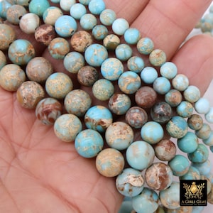 May include: A strand of turquoise and brown jasper beads. The beads are round and have a speckled pattern. The beads are strung on a clear elastic cord.