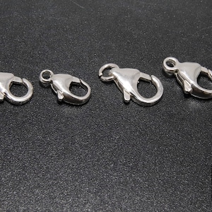 May include: Four silver lobster claw clasps of varying sizes. These clasps are commonly used for jewelry making.