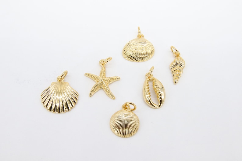 May include: Six gold-coloured metal charms in the shape of seashells and a starfish. The charms are perfect for jewellery making or adding a touch of nautical style to crafts.