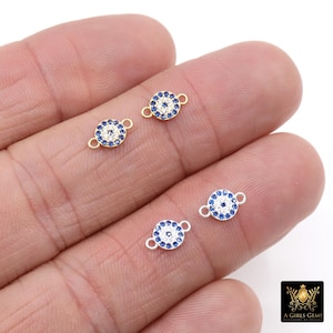 May include: Small gold and silver-toned charm connectors with a blue and white circular design. Each charm has two small loops for attaching to jewelry. The charms are displayed on a hand.