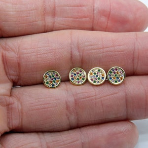 May include: Four gold-toned stud earrings with a round shape and a colorful, multi-faceted design. Each earring is set with small, round stones in various colors, including red, blue, green, and yellow.