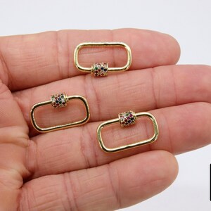 May include: Three gold-toned metal clasps with a colorful, multi-faceted stone design. The clasps are rectangular in shape with a rounded barrel in the center.
