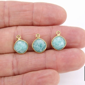 May include: Three gold-plated pendants with light blue, faceted, square-shaped amazonite gemstones. Each pendant has a loop for attaching to a chain or cord.