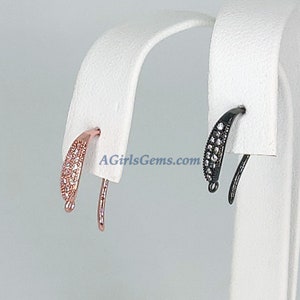 May include: Two pairs of earring hooks with a curved design. One pair is rose gold with clear cubic zirconia stones and the other pair is black with clear cubic zirconia stones. The earring hooks are displayed on a white stand. AGirlsGems.com is printed on the stand.