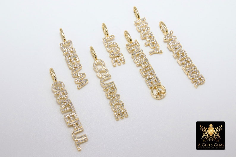 May include: A set of seven gold charm necklaces with different words spelled out in diamonds. The words are "Dream", "Love", "Happy", "Awesome", "Courage", "Grateful", and "Peace".