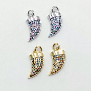 May include: Four gold and silver charm pendants in the shape of a tooth with colorful cubic zirconia stones. The charms are perfect for jewelry making.
